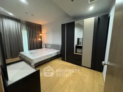 Modern bedroom with sleek furniture and wooden flooring in a stylish apartment.