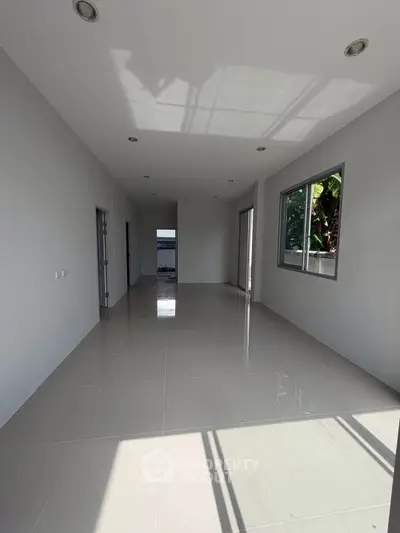 Spacious empty room with large windows and glossy tiled floors, ideal for customization.