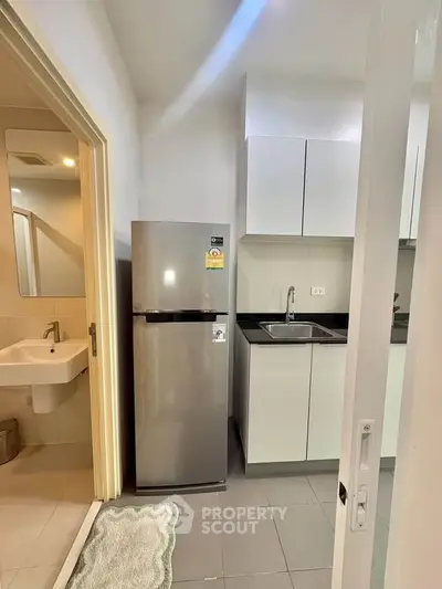 Modern compact kitchen with stainless steel fridge and sleek cabinetry
