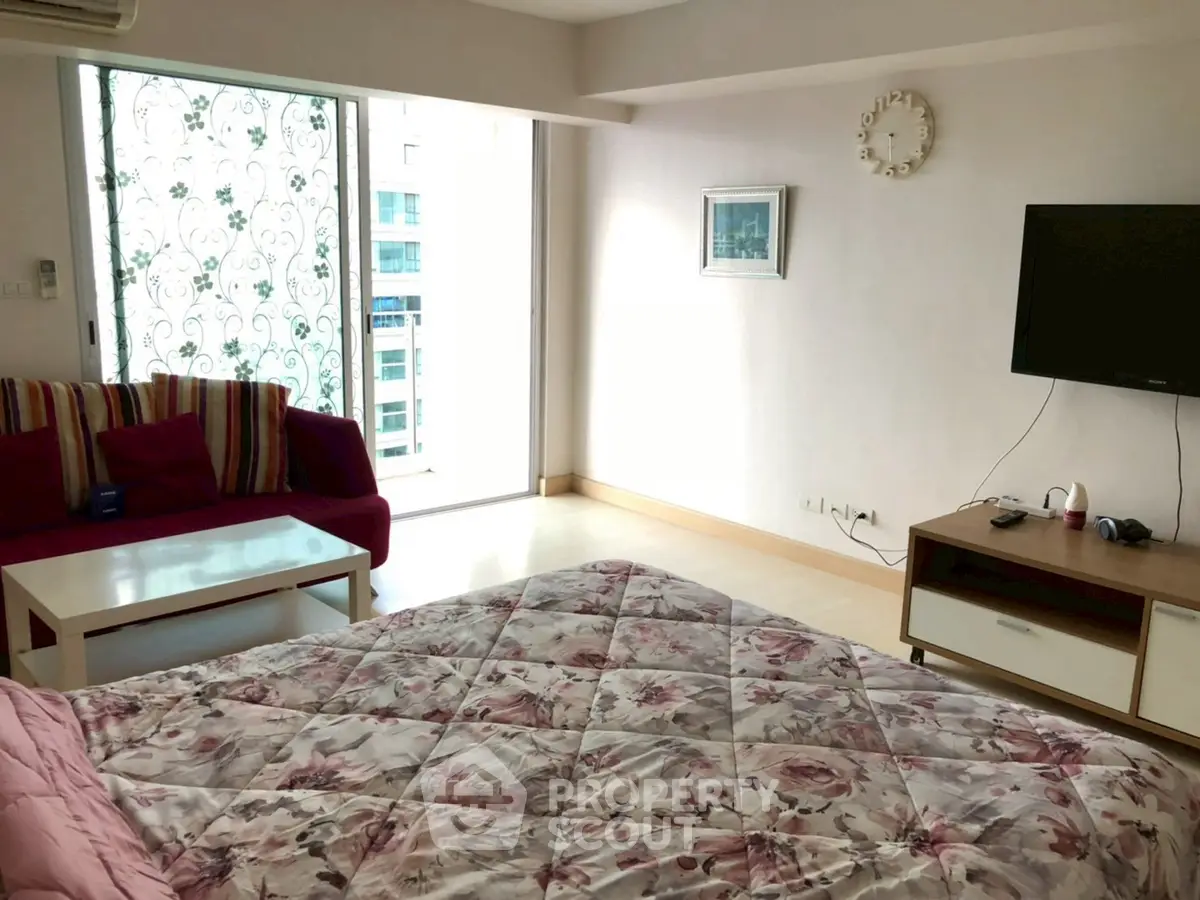 Spacious bedroom with modern decor and large window offering city views.