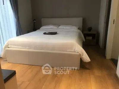 Cozy bedroom with modern decor and natural light, featuring a comfortable bed and wooden flooring.