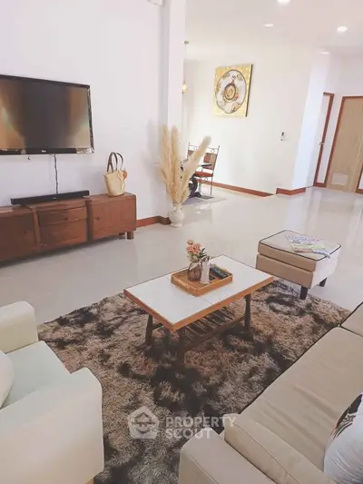 Spacious living room with modern decor, cozy seating, and wall-mounted TV, perfect for relaxation and entertainment.