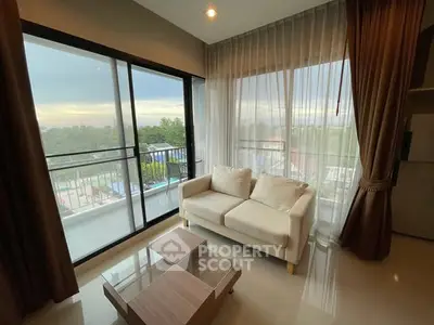 Modern living room with large windows and balcony view, featuring a cozy sofa and elegant curtains.