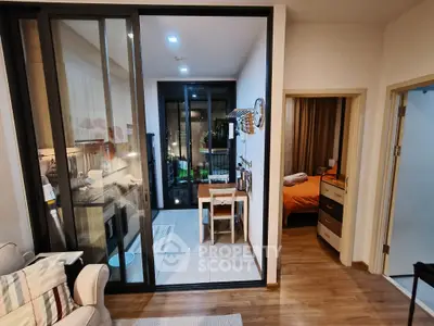 Modern apartment interior with open kitchen and cozy living area, featuring a small dining space and bedroom view.