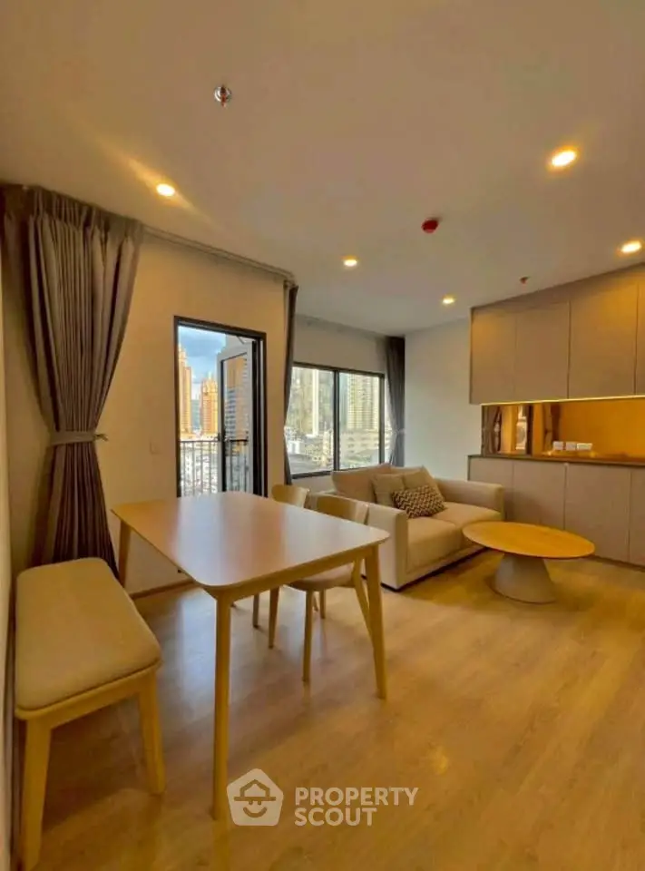 Modern living room with open layout and city view, featuring stylish furniture and natural lighting.