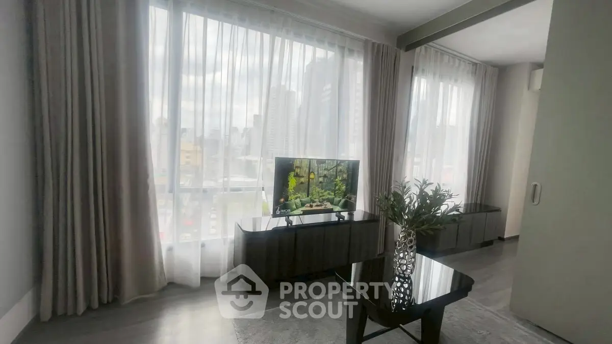 Modern living room with large windows and city view, featuring sleek furniture and stylish decor.