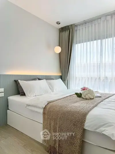 Modern bedroom with elegant decor and natural light, featuring a cozy bed and stylish lighting.