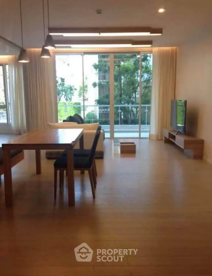 Spacious living room with modern decor and large windows overlooking greenery.