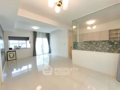 Spacious open-plan living room with modern kitchen and large windows.