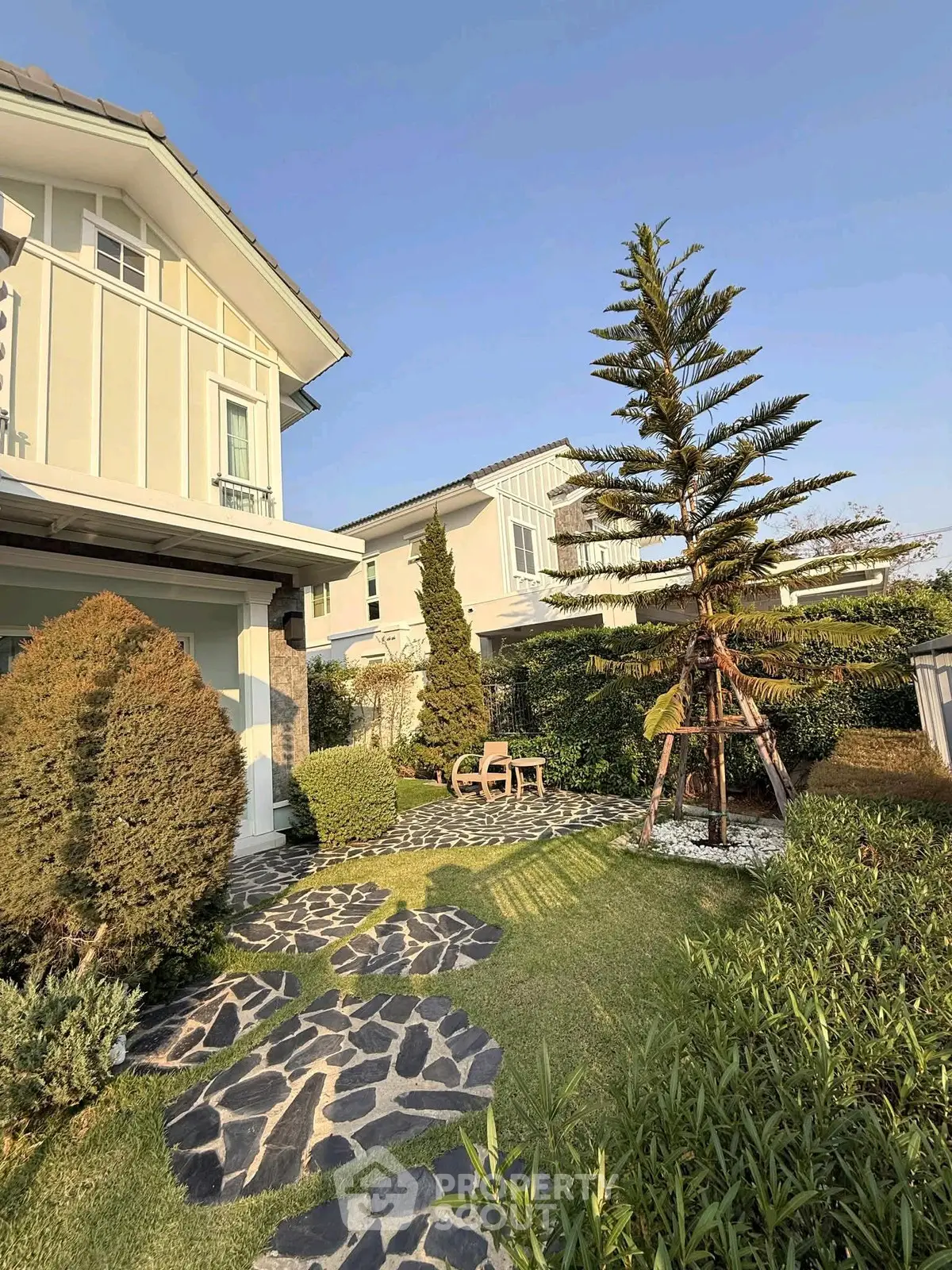 Charming suburban home with lush garden and stone pathway, perfect for outdoor relaxation.