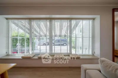 Spacious living room with large window and cozy seating area, offering a bright and inviting atmosphere.