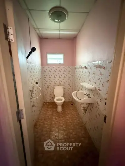 Compact bathroom with floral tiles and basic fixtures in cozy real estate property.