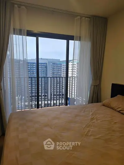 Modern bedroom with large window offering stunning city view in high-rise apartment.