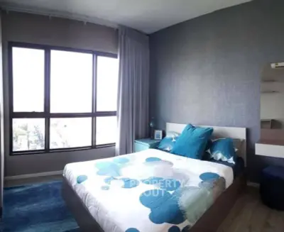 Modern bedroom with large window and stylish decor in a cozy apartment.