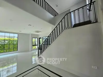 Spacious modern living room with elegant staircase and large windows