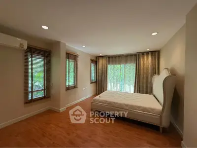Spacious bedroom with large windows and elegant bed frame, offering serene natural light.