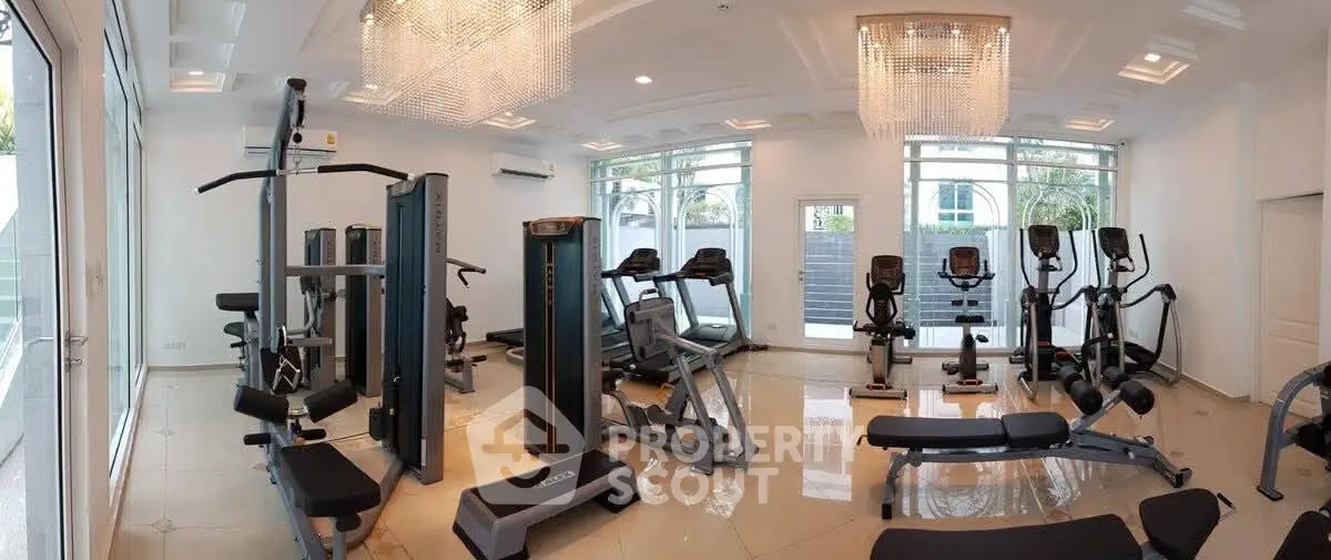 Luxurious gym with modern equipment and elegant chandeliers in a high-end residential building.