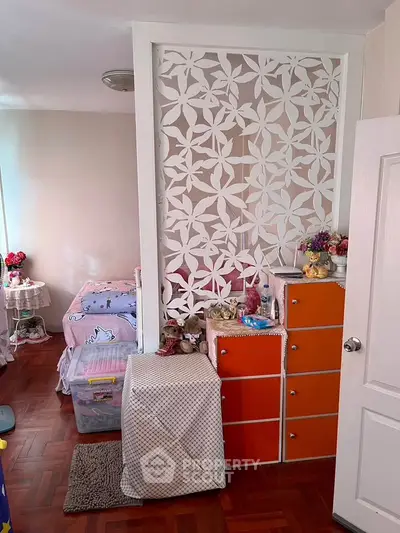 Charming bedroom with floral partition and vibrant orange storage, perfect for a cozy and stylish living space.