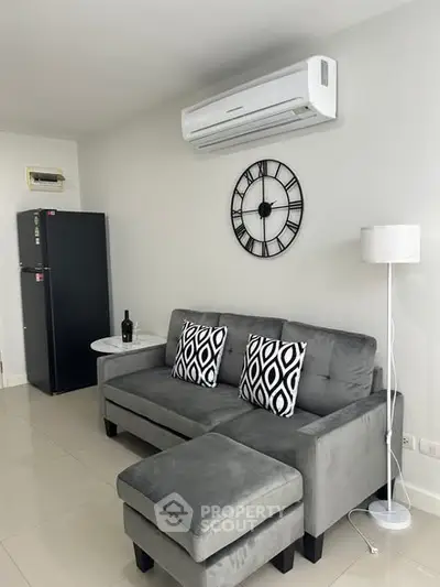 Modern living room with stylish gray sofa, wall clock, and air conditioning unit.