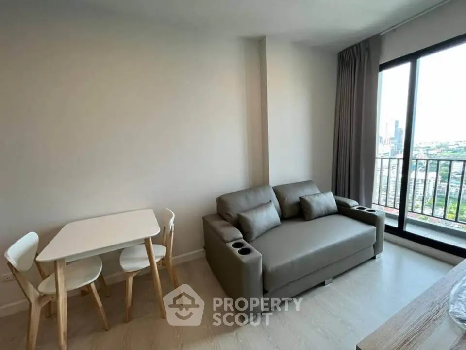 Modern living room with sleek sofa and dining set, featuring a stunning city view from the balcony.