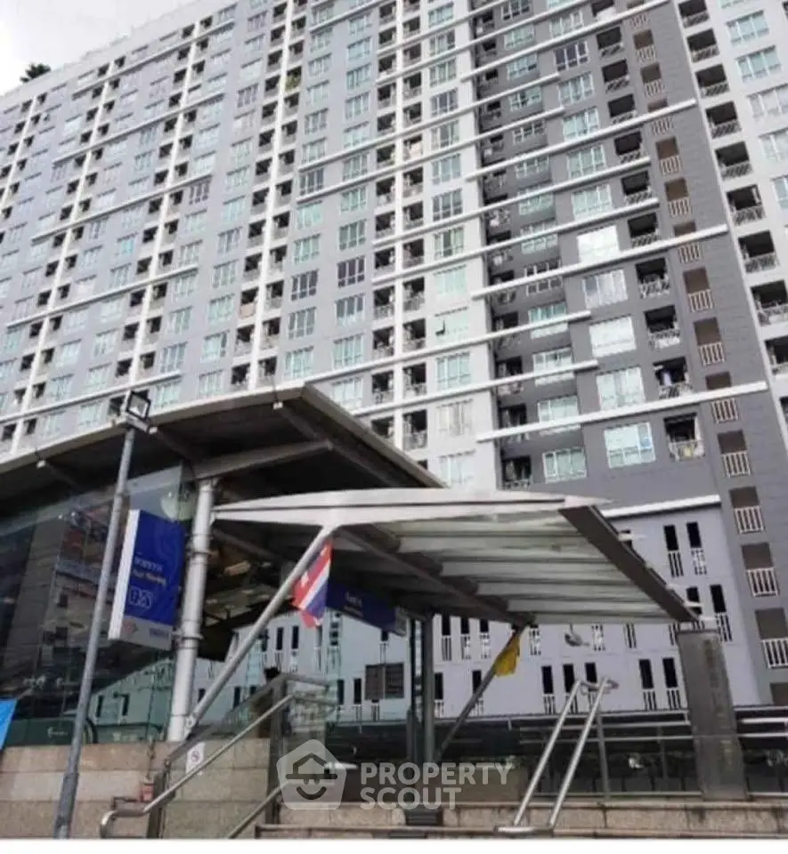 Modern high-rise building exterior with glass entrance and urban surroundings.