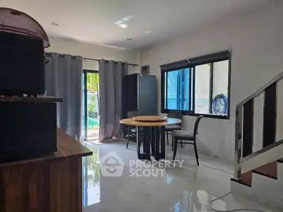 Modern living room with sleek design and natural light, featuring a round dining table and large windows.
