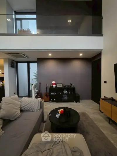 Modern living room with high ceiling and stylish decor, featuring a cozy sofa and entertainment area.