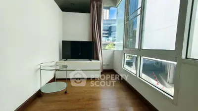 Modern living room with large windows and sleek TV stand in urban apartment.