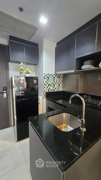 Modern kitchen with sleek black countertops and stylish cabinetry in a contemporary apartment.