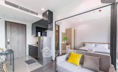 Modern open-plan studio apartment with sleek kitchen and cozy living area, featuring stylish decor and natural light.
