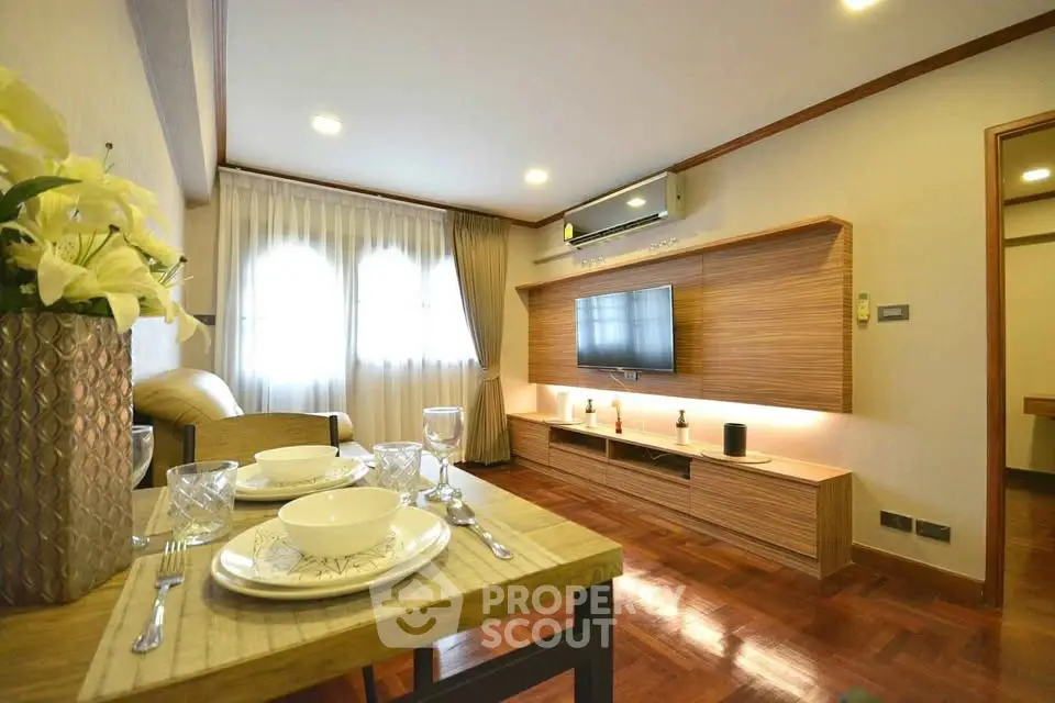 Elegant living room with modern decor and wooden flooring, featuring a wall-mounted TV and dining setup.
