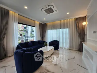 Luxurious living room with elegant blue sofa and large windows offering natural light.