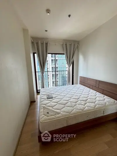 Modern bedroom with large window and city view, featuring a wooden bed frame and minimalist decor.