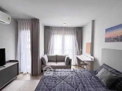 Modern bedroom with cozy sofa and study area, featuring large windows and elegant curtains.