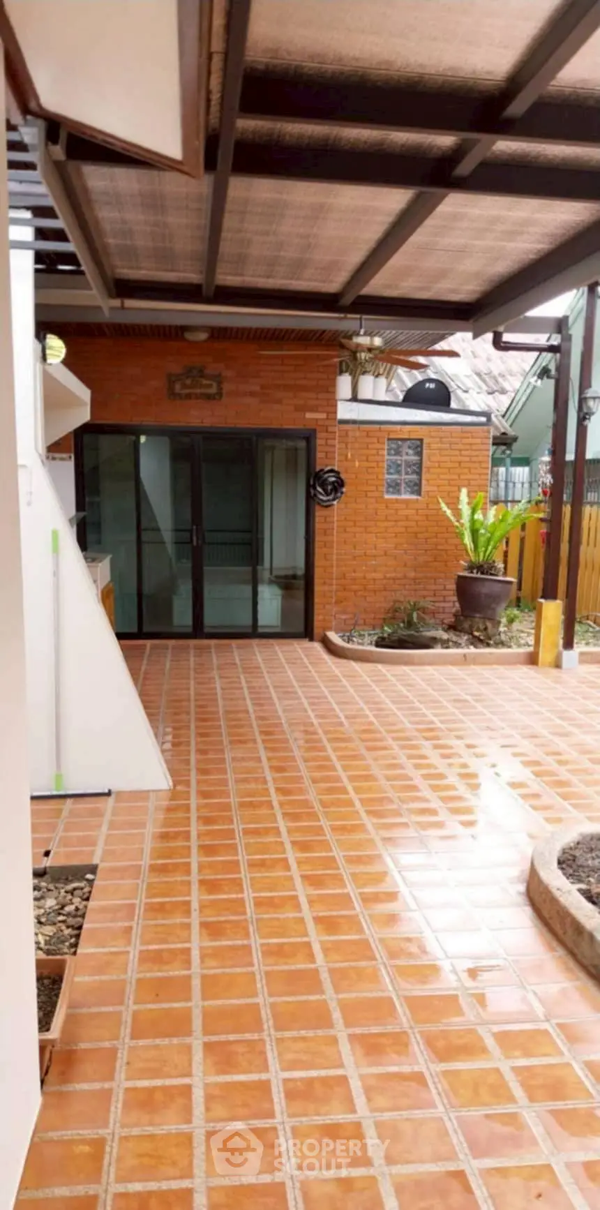 Charming outdoor patio with terracotta tiles and covered roof, perfect for relaxation.