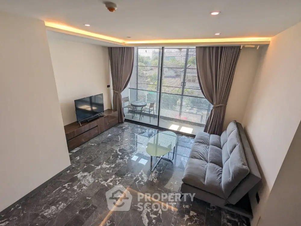 Modern living room with marble flooring and large windows offering natural light.