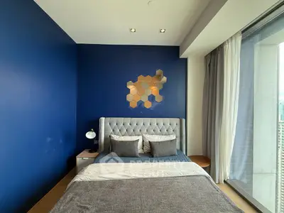 Modern bedroom with blue accent wall and large window offering city views.