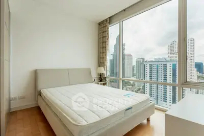 Modern bedroom with large window offering stunning city views in a high-rise apartment.