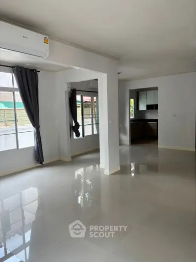 Spacious open-plan living area with large windows and modern kitchen.