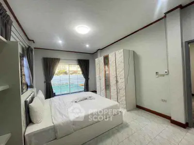 Spacious bedroom with modern decor and large window offering natural light.