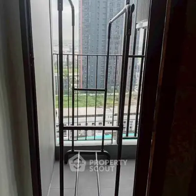 Compact balcony with city view, ideal for urban living, featuring a drying rack and modern railing.