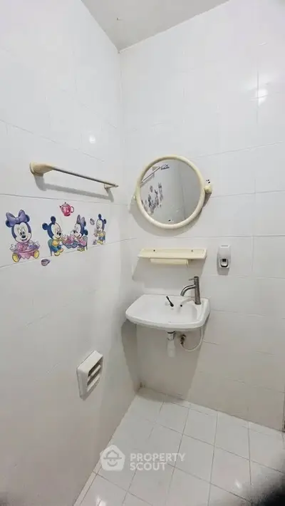 Charming small bathroom with playful cartoon wall decals and round mirror, perfect for a cozy home.