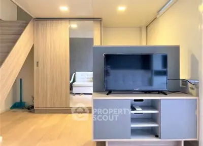 Modern living room with sleek TV stand and mirrored wardrobe under staircase.