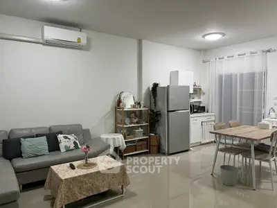 Modern open-layout living room with kitchen, featuring sleek furniture and appliances.