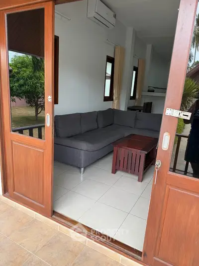 Inviting living room with cozy sectional sofa and wooden sliding doors opening to a lush garden view.