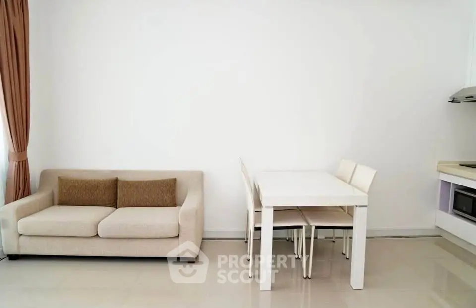 Modern minimalist living room with beige sofa and dining area in open layout.