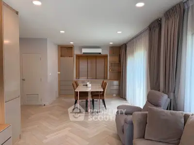Modern living room with elegant furniture and natural light, featuring a cozy seating area and stylish dining space.