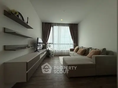 Modern living room with sleek furniture and large window offering natural light.