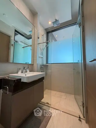 Modern bathroom with glass shower enclosure and sleek vanity in luxury apartment.