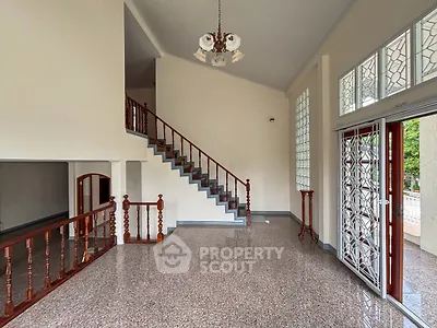 Spacious living room with elegant staircase and large windows